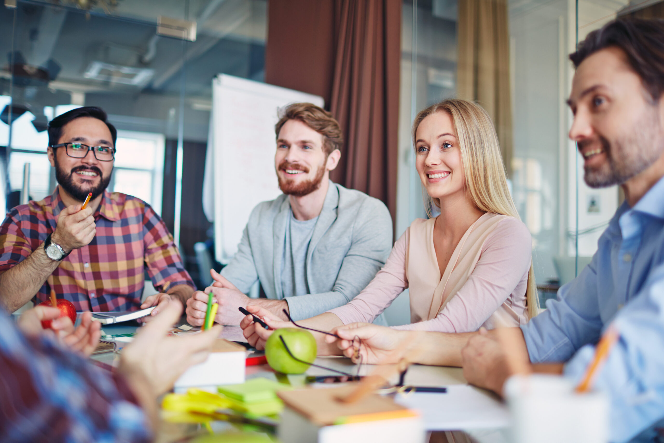 Group of professionals smiling during a collaborative meeting in a modern office setting.