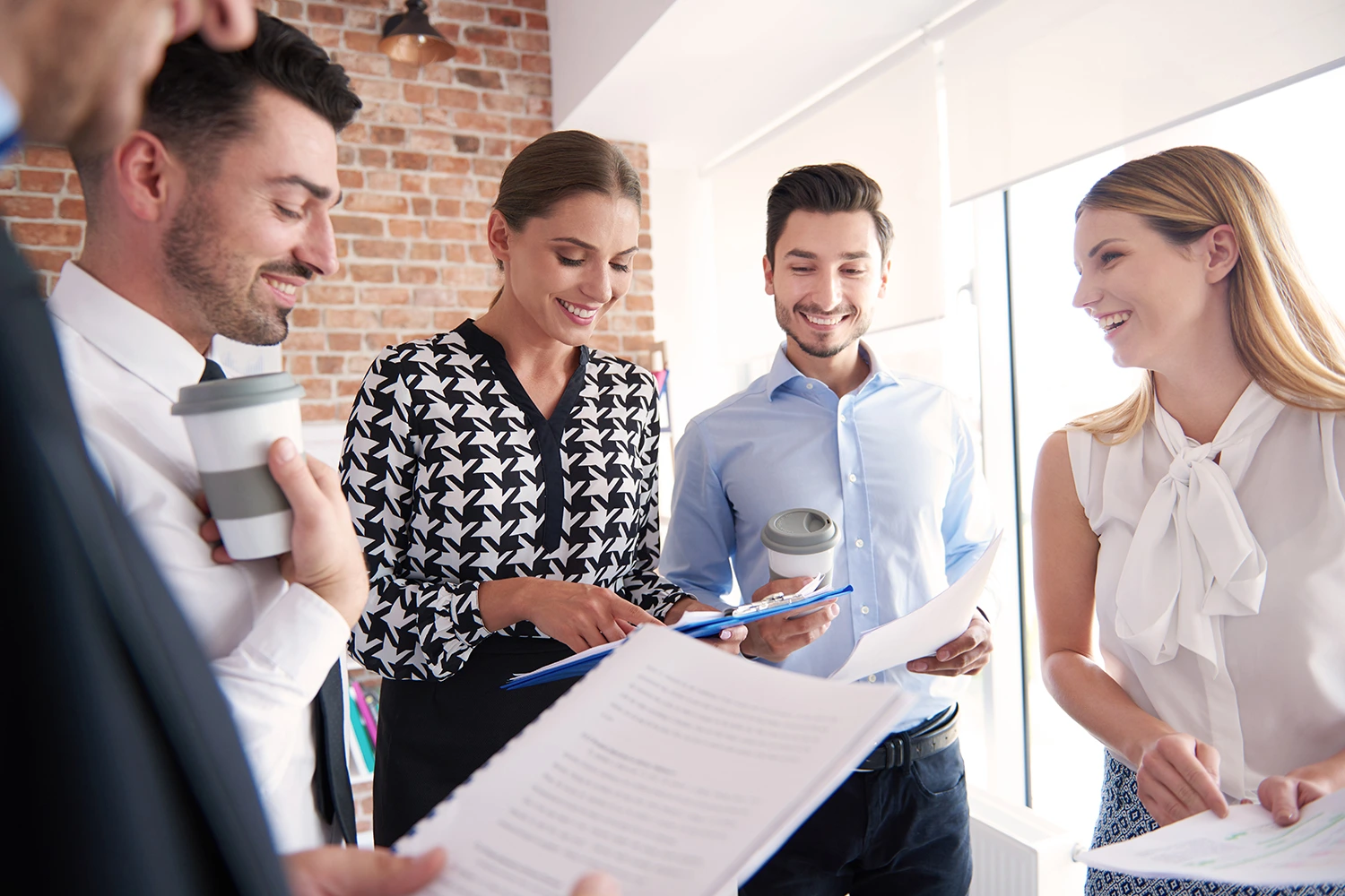 Group of professionals standing in office reviewing recruitment documents and collaborating