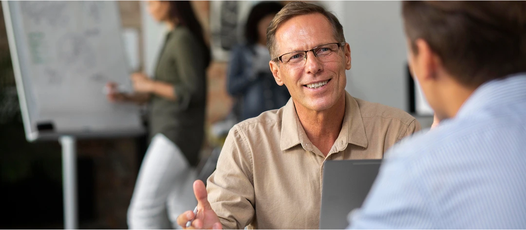 Smiling manager having a one-on-one discussion in an office environment, emphasizing communication, workplace integrity, and assessment of skills.