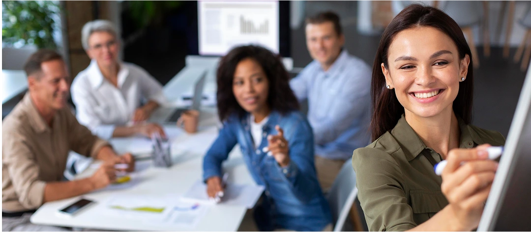 Group of colleagues in a meeting with a woman writing on a flip chart, illustrating teamwork, collaboration, and skill assessment in a professional setting.