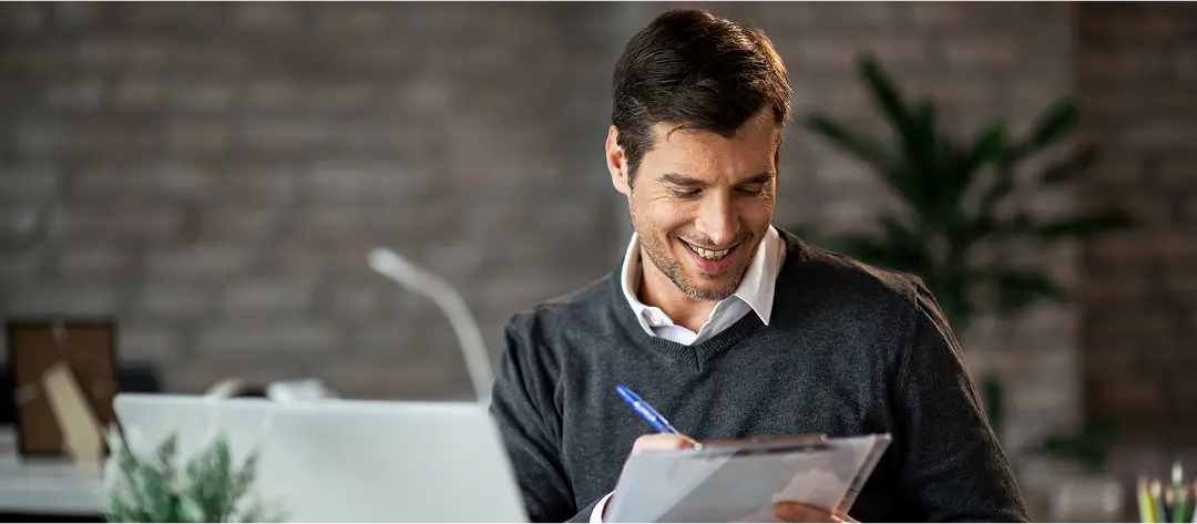 Businessman reviewing documents with a smile in a modern office, representing skill evaluation, assessment accuracy, and workplace productivity tests.
