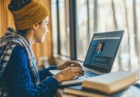 An HR professional is watching a one-way video interview of a candidate on a laptop.