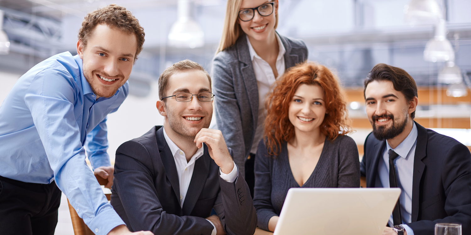 Team of young professionals smiling during a business meeting in a modern office.
