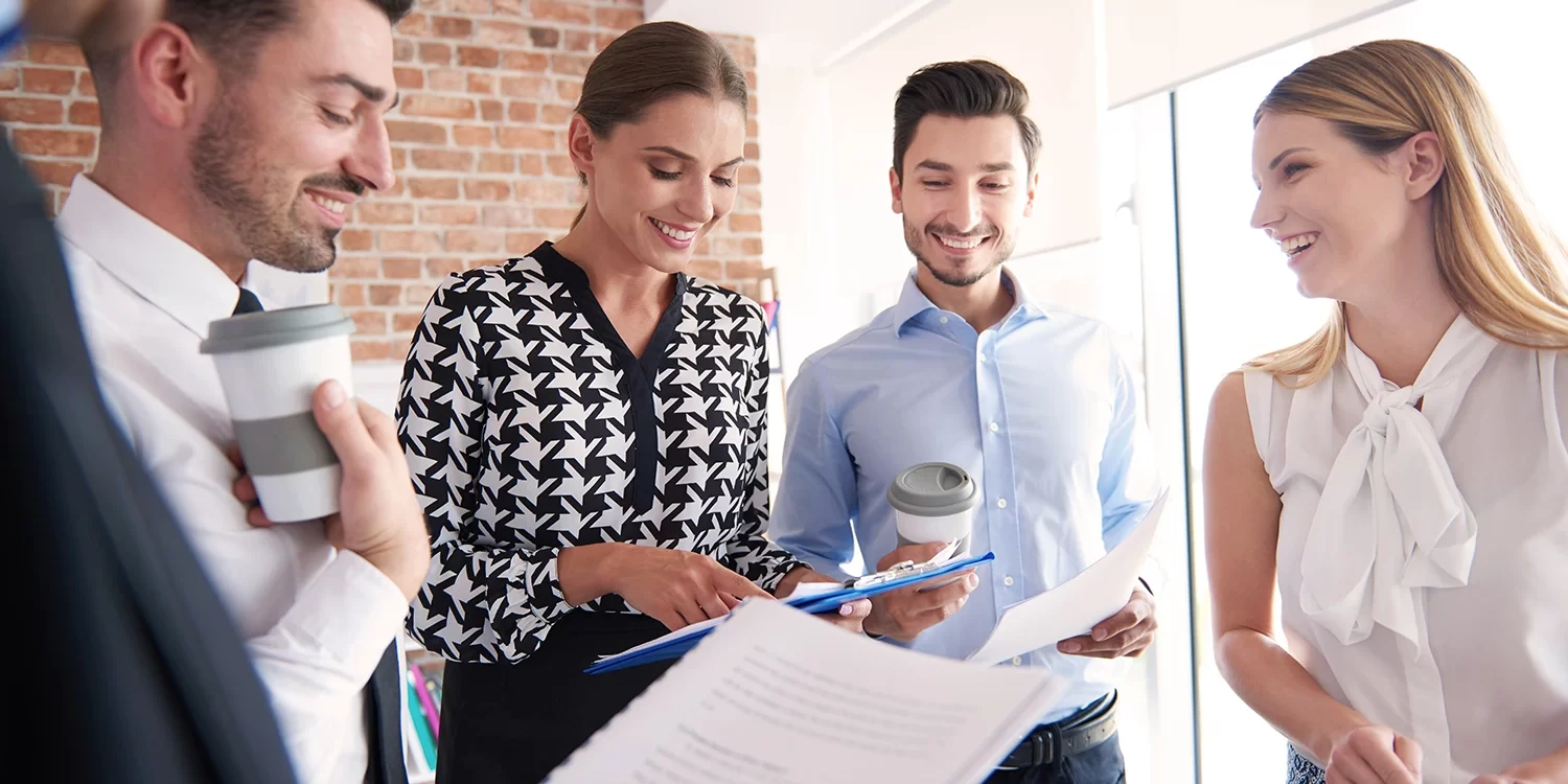 Group of professionals standing in office reviewing recruitment documents and collaborating