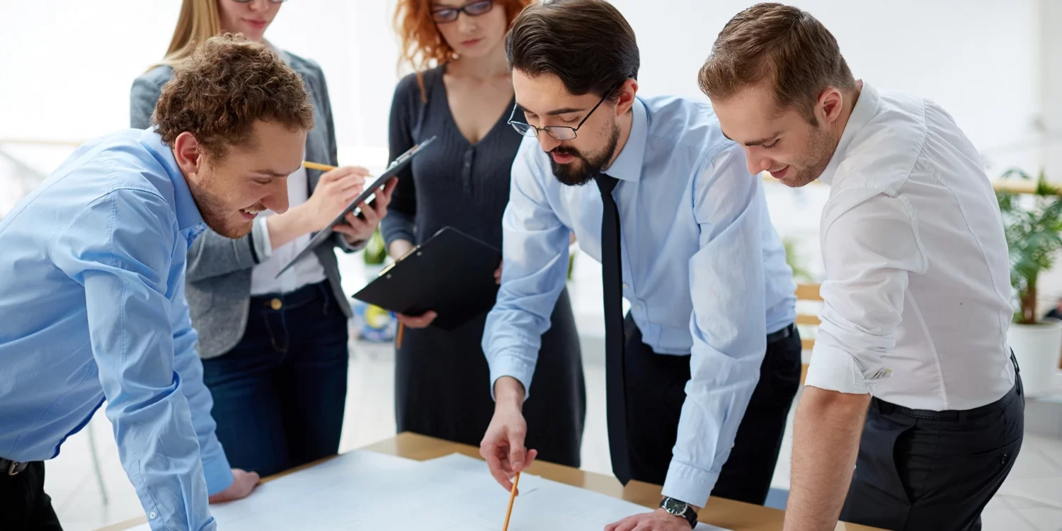 Team of business professionals analyzing hiring blueprints during a meeting
